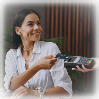 Woman smiling and tapping her credit card to a mobile point-of-sale.