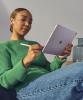 A woman holding an iPad Air holding an Apple Pencil.